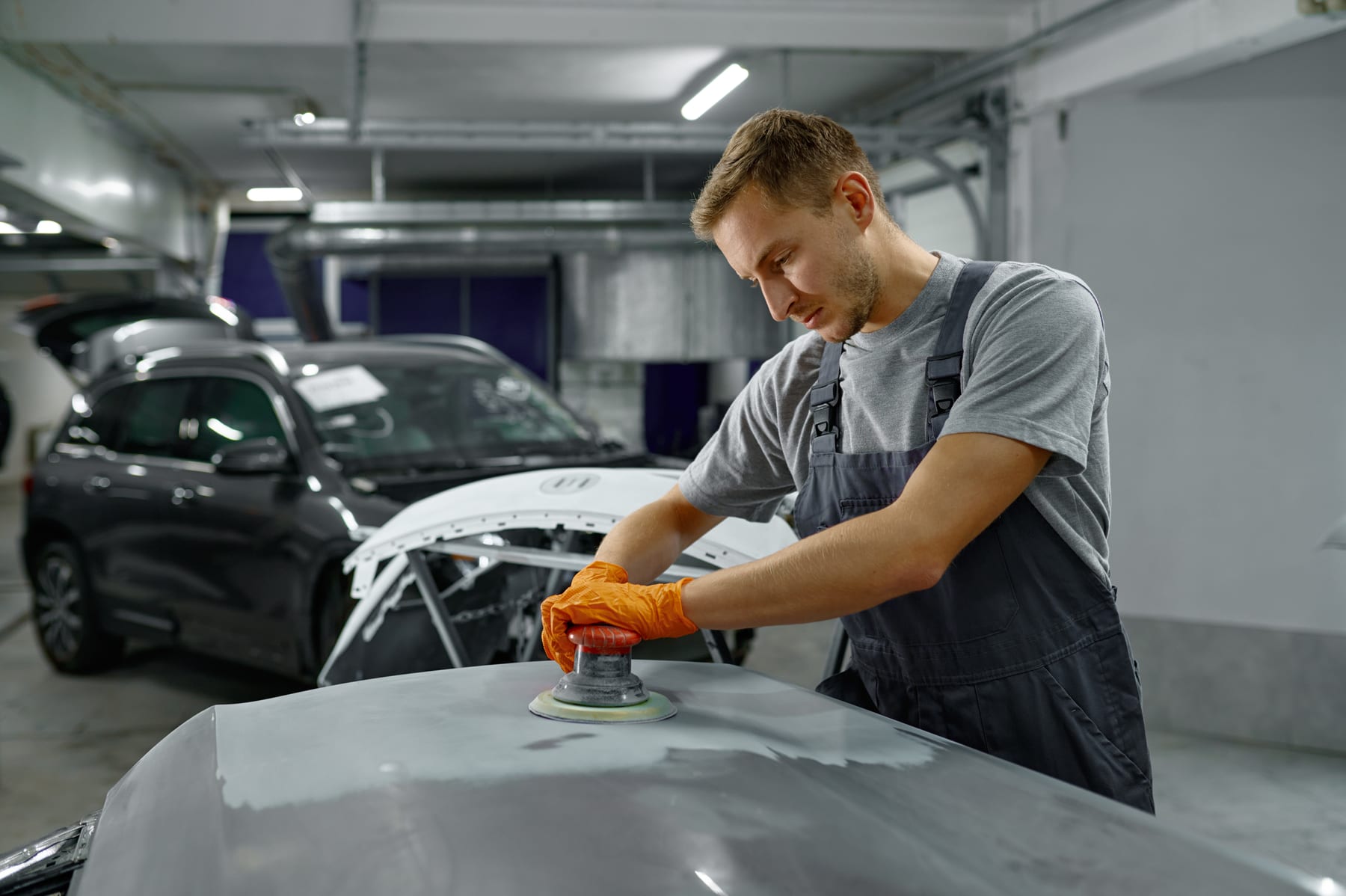Collision technician refinishing a car body panel in a repair shop