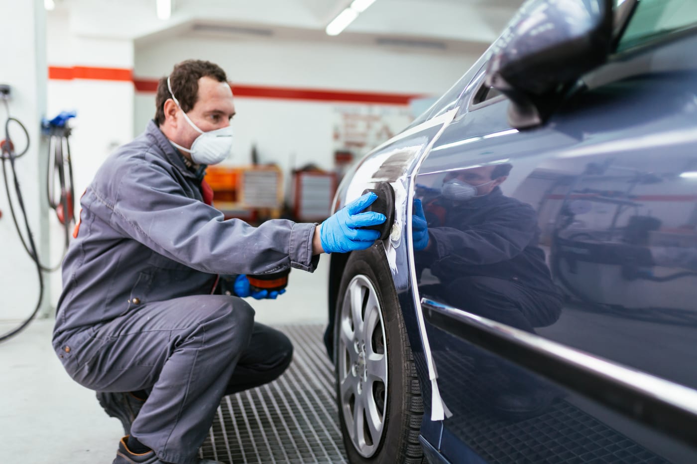 Collision technician detailing a car body panel in a repair shop